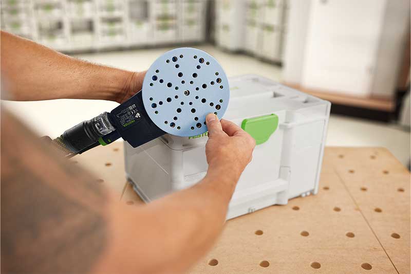 Een man monteert een Granat-schuurmateriaal op de steunschijf