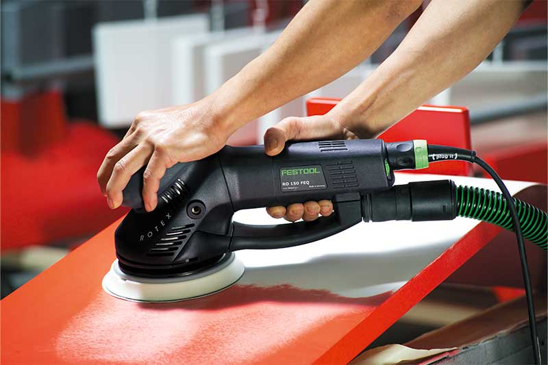 Een rood oppervlak wordt met behulp van een Rotex-schuurmachine bewerkt