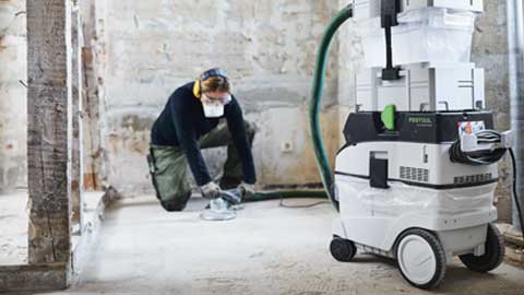Een vakman schuurt een vloer en gebruikt het Festool vloerschuursysteem met afzuiging.