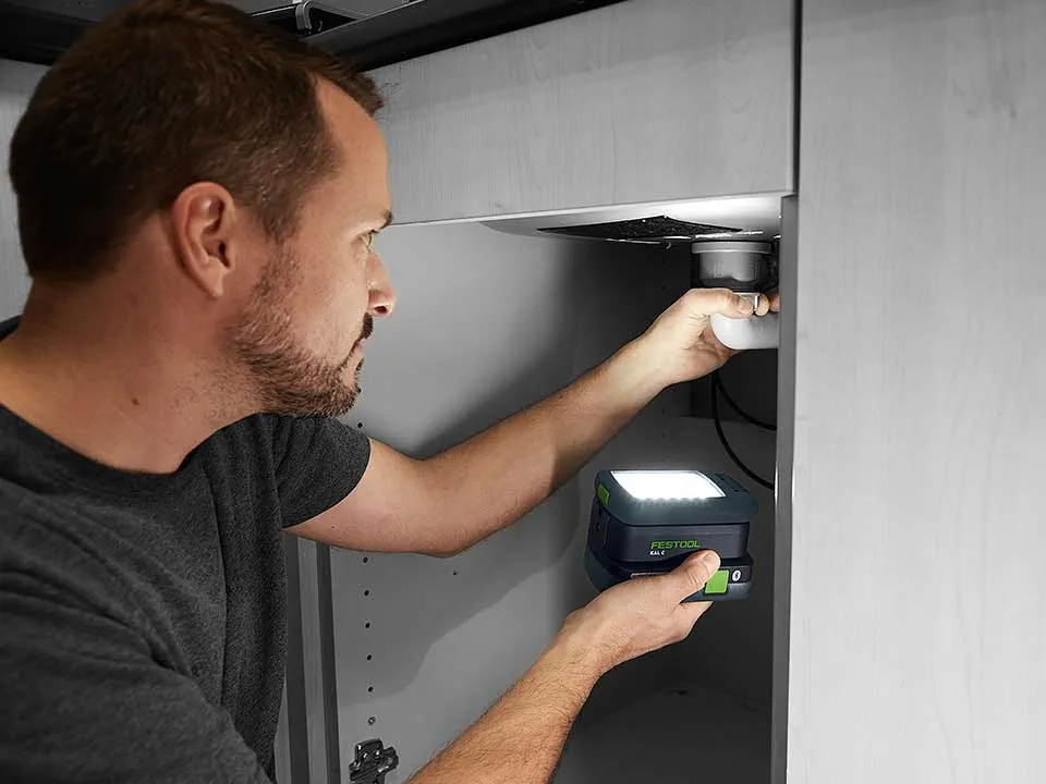 Een man verlicht de aansluiting van een wastafel met de SYSLITE KAL 2