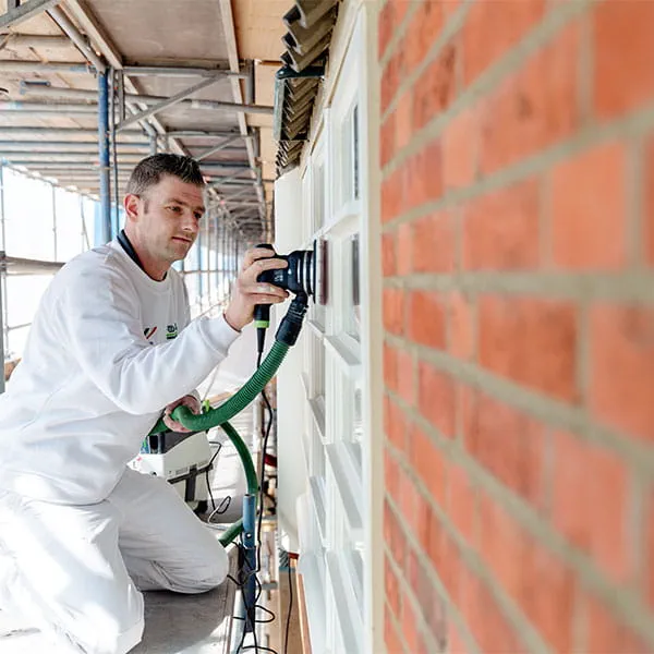 Een medewerker van Wolters bij de renovatie van raamkozijnen.