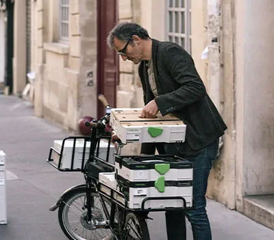 Na gedane arbeid pakt de bijzondere meubelmaker zijn werkplaats in en gaat weer met zijn fiets op pad door de straten van Parijs.