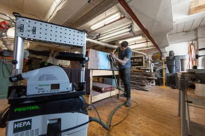 Het oppervlak van een 'River Table' wordt afgeschuurd met de Festool excenterschuurmachine