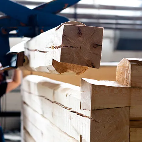 Een houten balk wordt met de kraan naar de locatie gebracht.